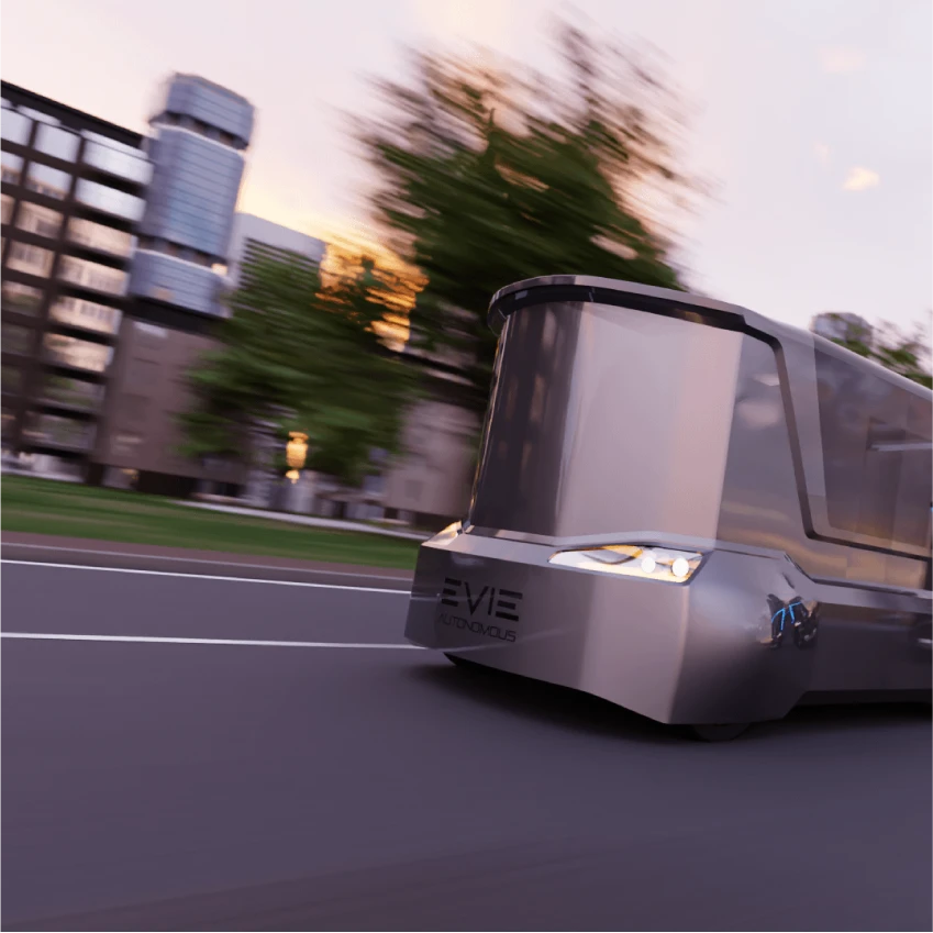 A bronze EVIE passenger pod at speed, the city behind it blurred by the motion